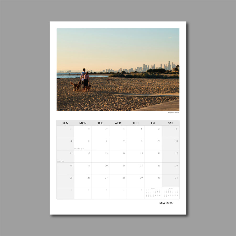 A3 Wall Calendar: Captivating Vistas featuring a couple with dog walking along the beach at golden hour with the city skyline as a backdrop