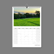 A4 Wall Calendar: Marvellous Melbourne featuring a lone runner with green grass in foreground and city skyline in distance