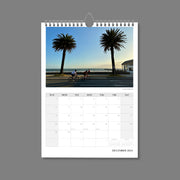 A4 Wall Calendar: Marvellous Melbourne featuring cyclists riding along the road next to the bay with palm trees