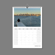 A4 Wall Calendar: Marvellous Melbourne featuring back view of man sitting on a platform looking over the bay to city skyline sunlit