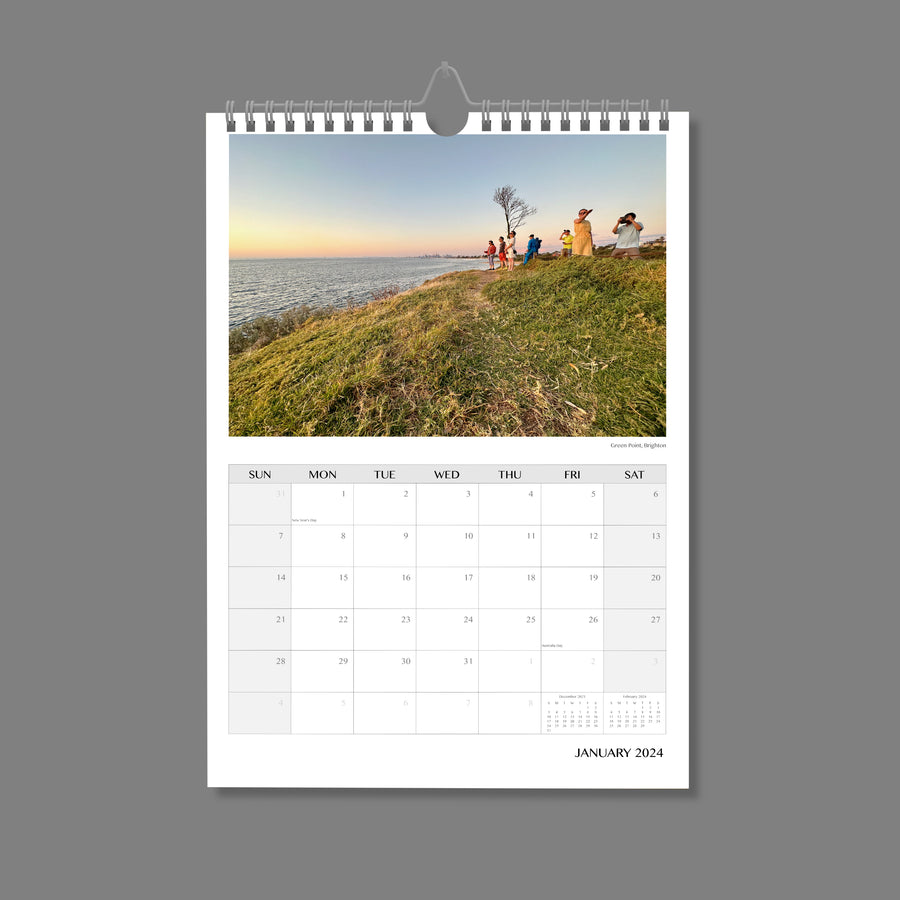 A4 Wall Calendar: Marvellous Melbourne featuring people on top of a grassed hill looking out to the bay at sunset