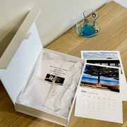 sturdy white box with lid open and a5 calendar cards tucked inside with tissue paper and twine