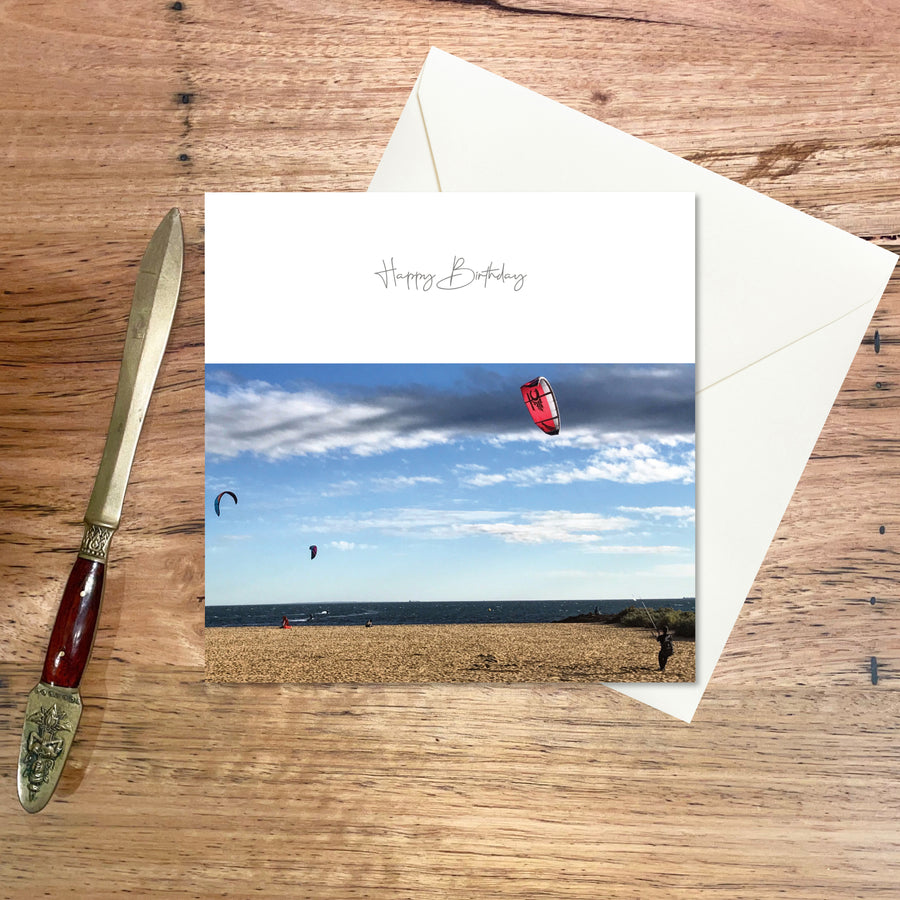 Birthday Greeting Card: Kite Surfers, a card featuring kite surfers at the beach with a striking sky backdrop on a winter’s day