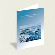 Designer Greeting Card: Jumping Dolphins featuring graceful dolphins in the blue-green ocean waters with a nature quote