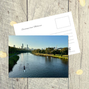 Postcard from Melbourne: Yarra River, a landscape postcard featuring a lone kayak on the cool blue river next to parklands in early evening