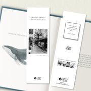 A two sided 200 x 60 bookmark displayed inside a book, featuring a Euro style laneway with man and dog in classic B&W with white background variant