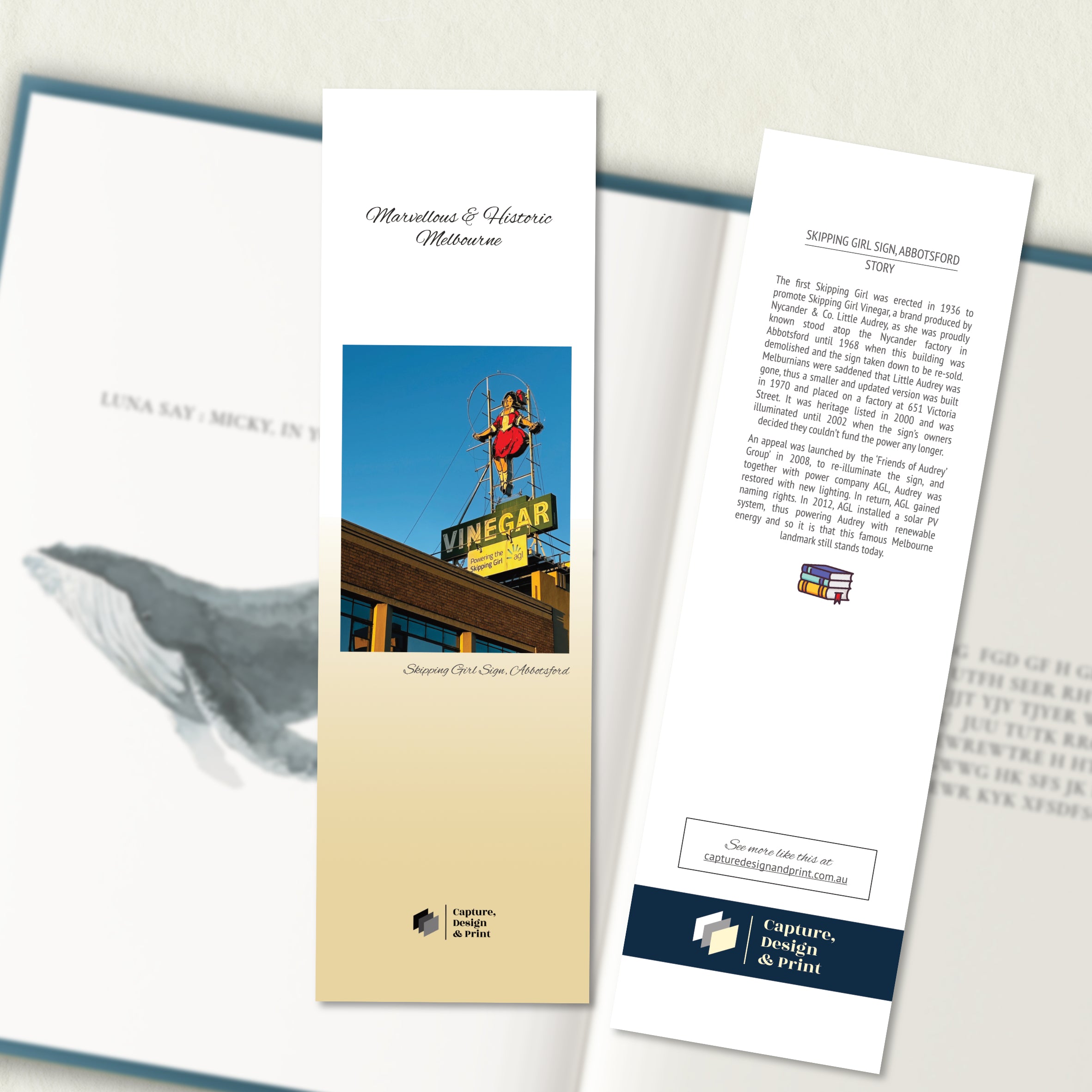 A two sided 200 x 60 bookmark in colour displayed inside a book, featuring the iconic little skipping girl sign atop a factory