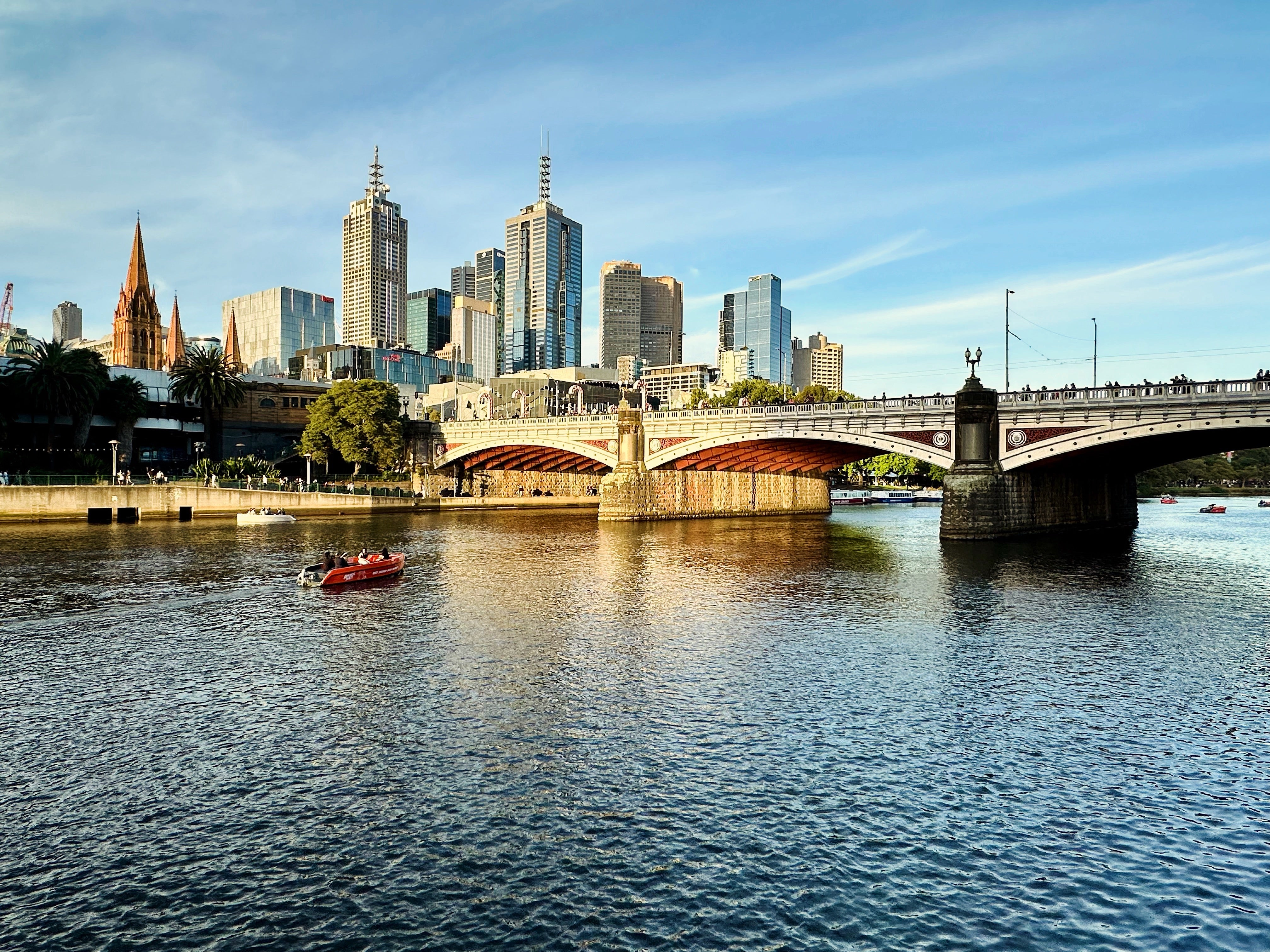 a bridge over the river with city buildings in the background golden lit