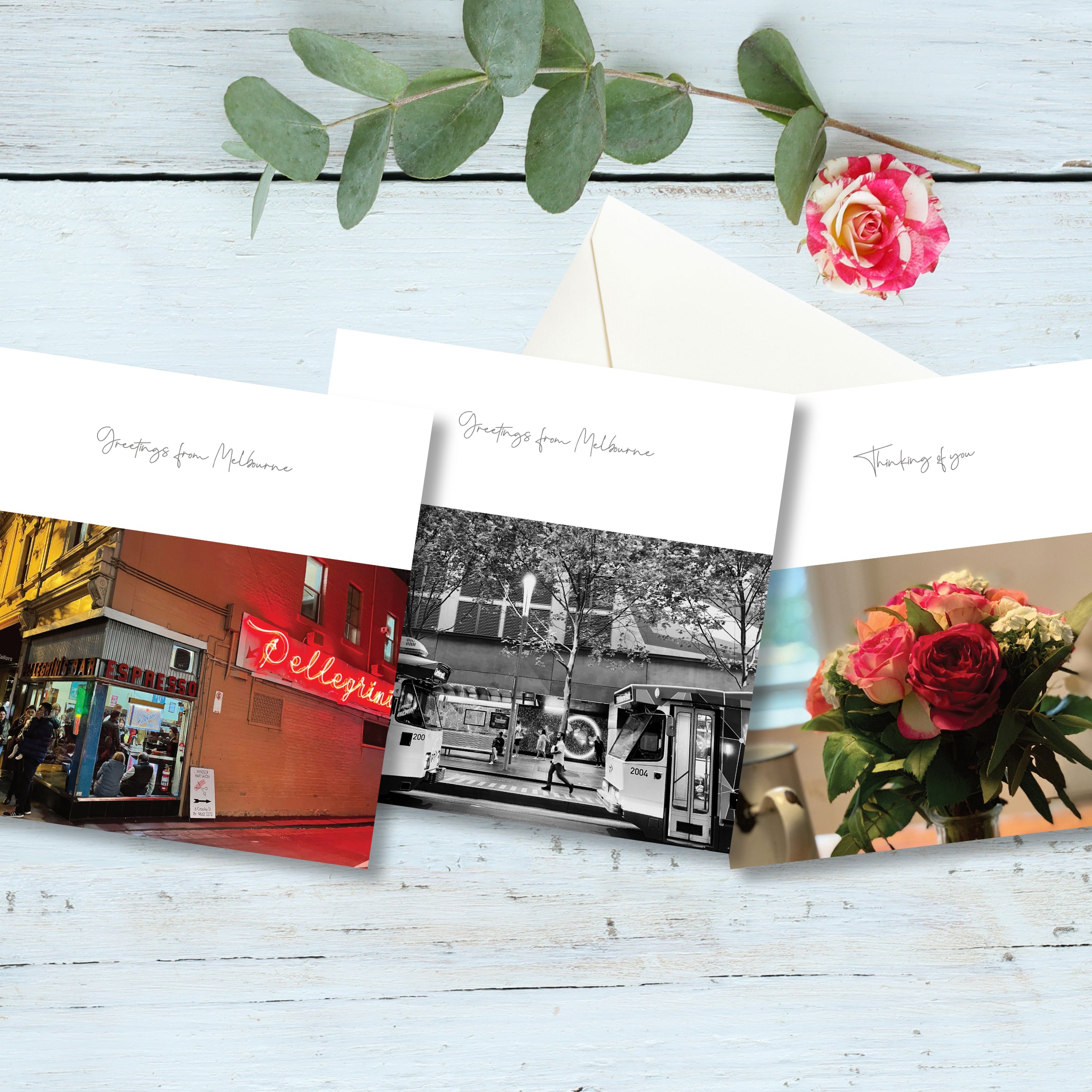 A selection of 3 small square greeting cards displayed on a rustic board background with a flower