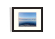 Frame mount with print of fisherman in shallow waters and a pretty sky in finalised picture frame hanging on wall