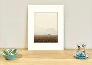 Frame mount containing a colour print of 3 sheep far away in a paddock with a smoke haze sitting upright on sideboard