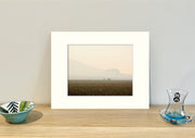 Frame mount containing a colour print of 3 sheep far away in a pasture with a smoke haze sitting upright on sideboard