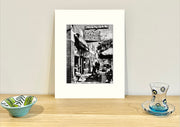 Frame mount containing a B&W print of a cool cafe in Richmond sitting upright on sideboard with objets d’art to the sides