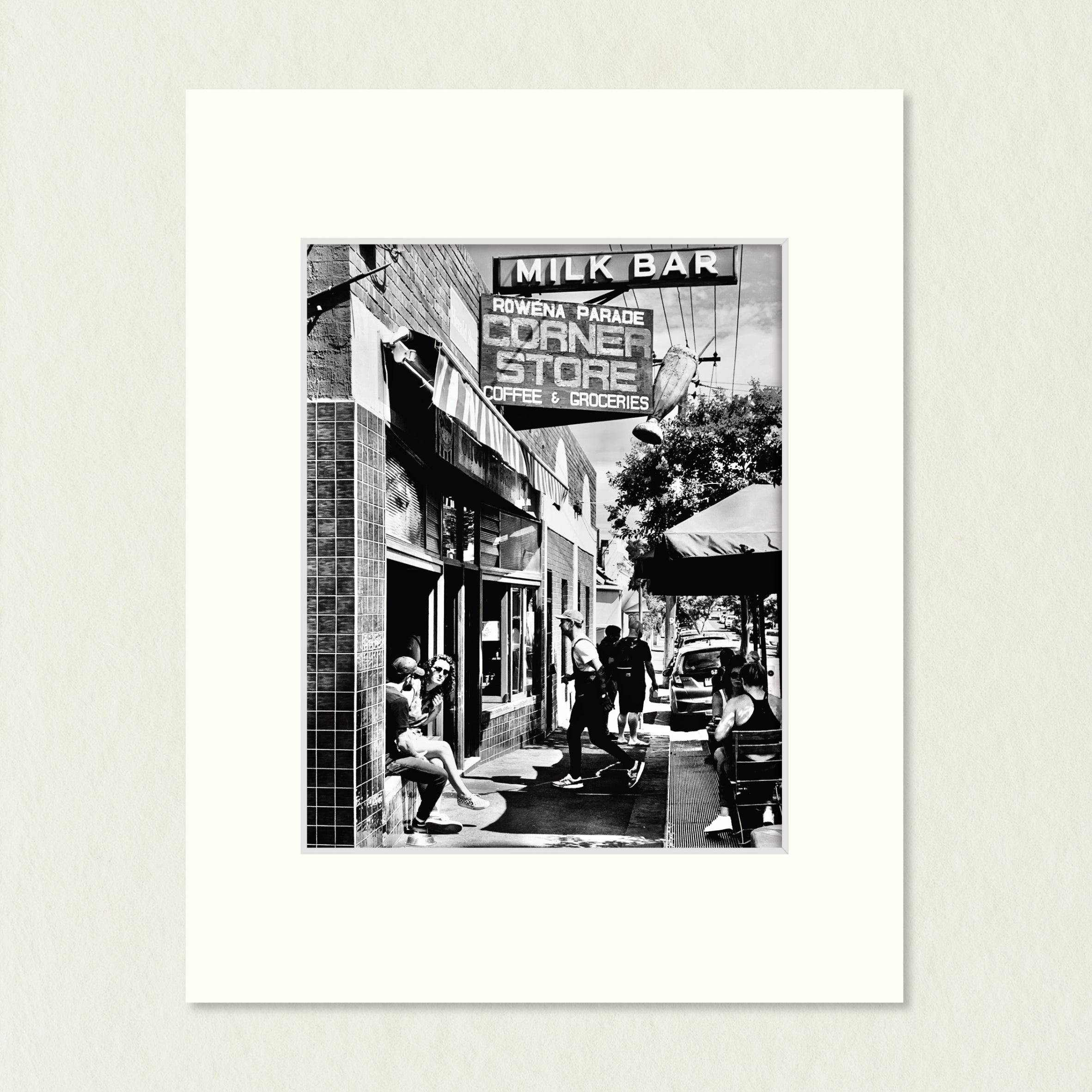 Ready to Frame Print: Rowena Parade - frame mount containing a B&W print of a busy   sidewalk outside a modern café in a quiet street