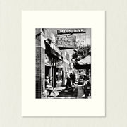 Ready to Frame Print: Rowena Parade - frame mount containing a B&W print of a busy   sidewalk outside a modern café in a quiet street