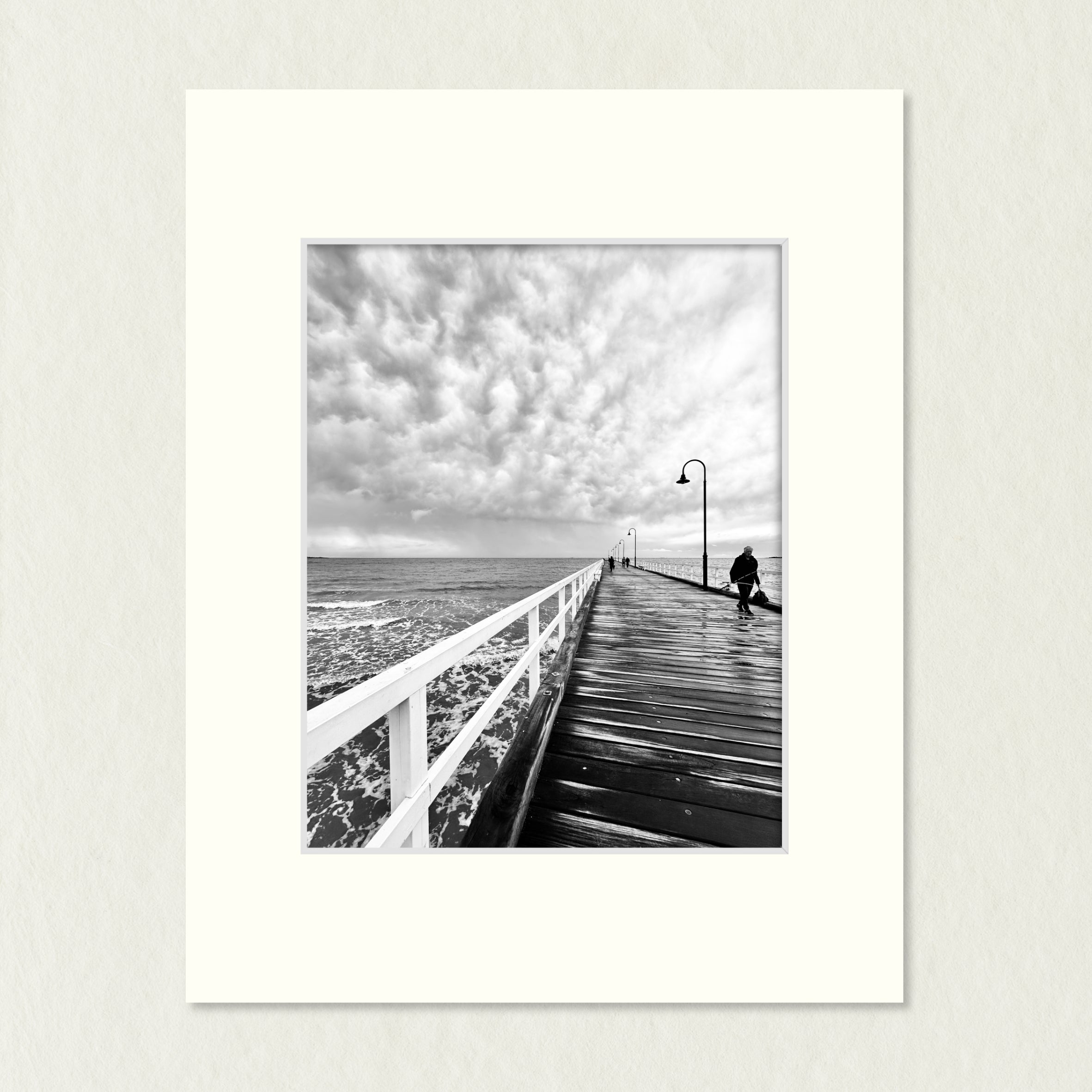 Ready to Frame Print: Storm Clouds Rolling- frame mount containing a B&W print of dramatic storm clouds over the pier with a lone fisherman